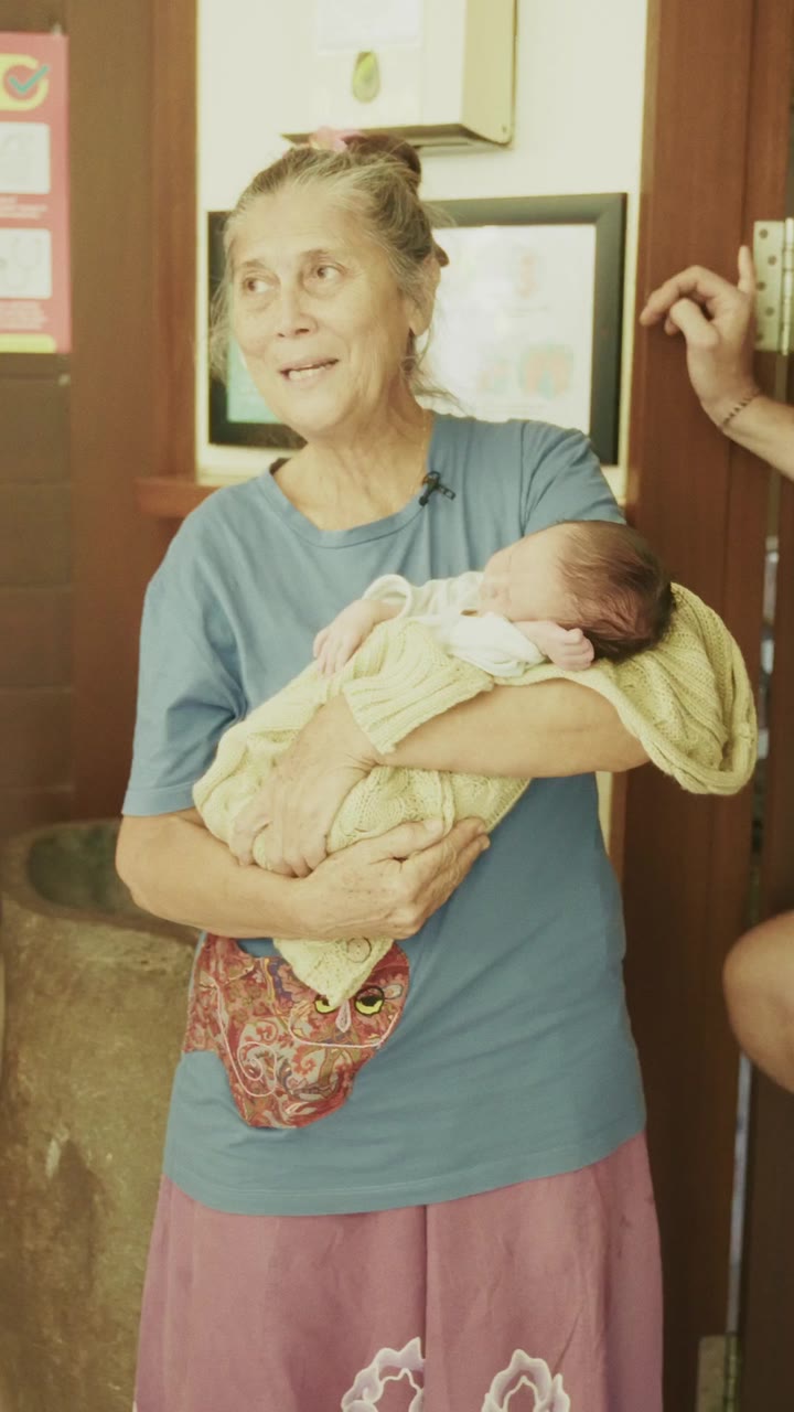 Une professionnelle de la naissance tient un nouveau-né à la porte de la clinique