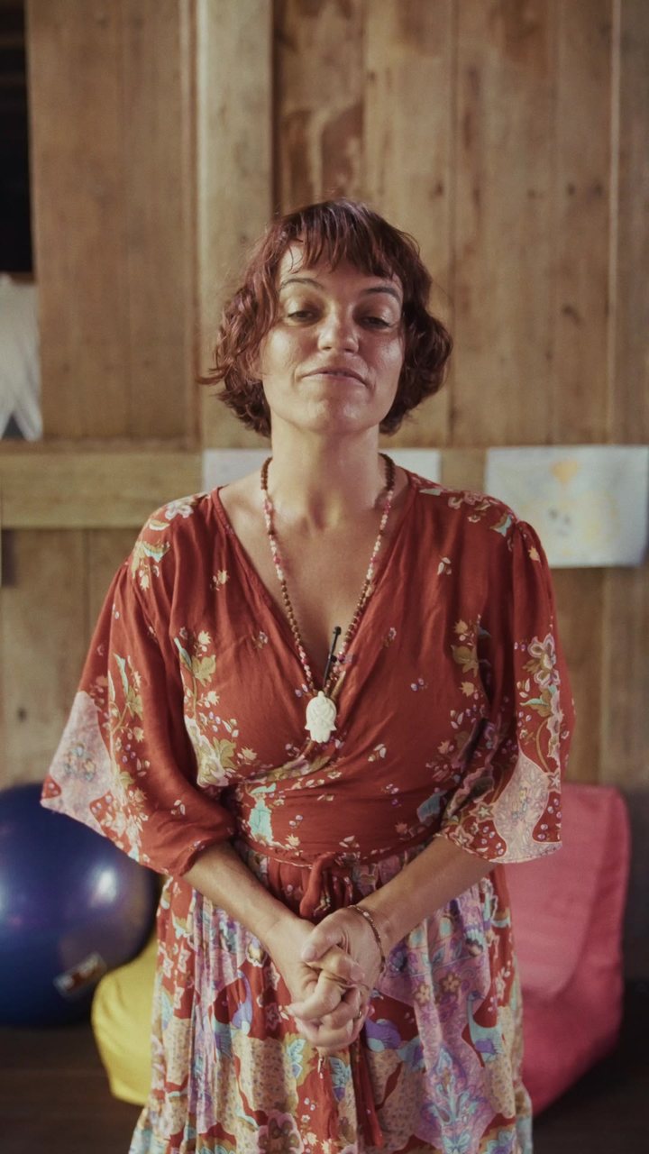 Une doula en robe rouge sous un toit de bois