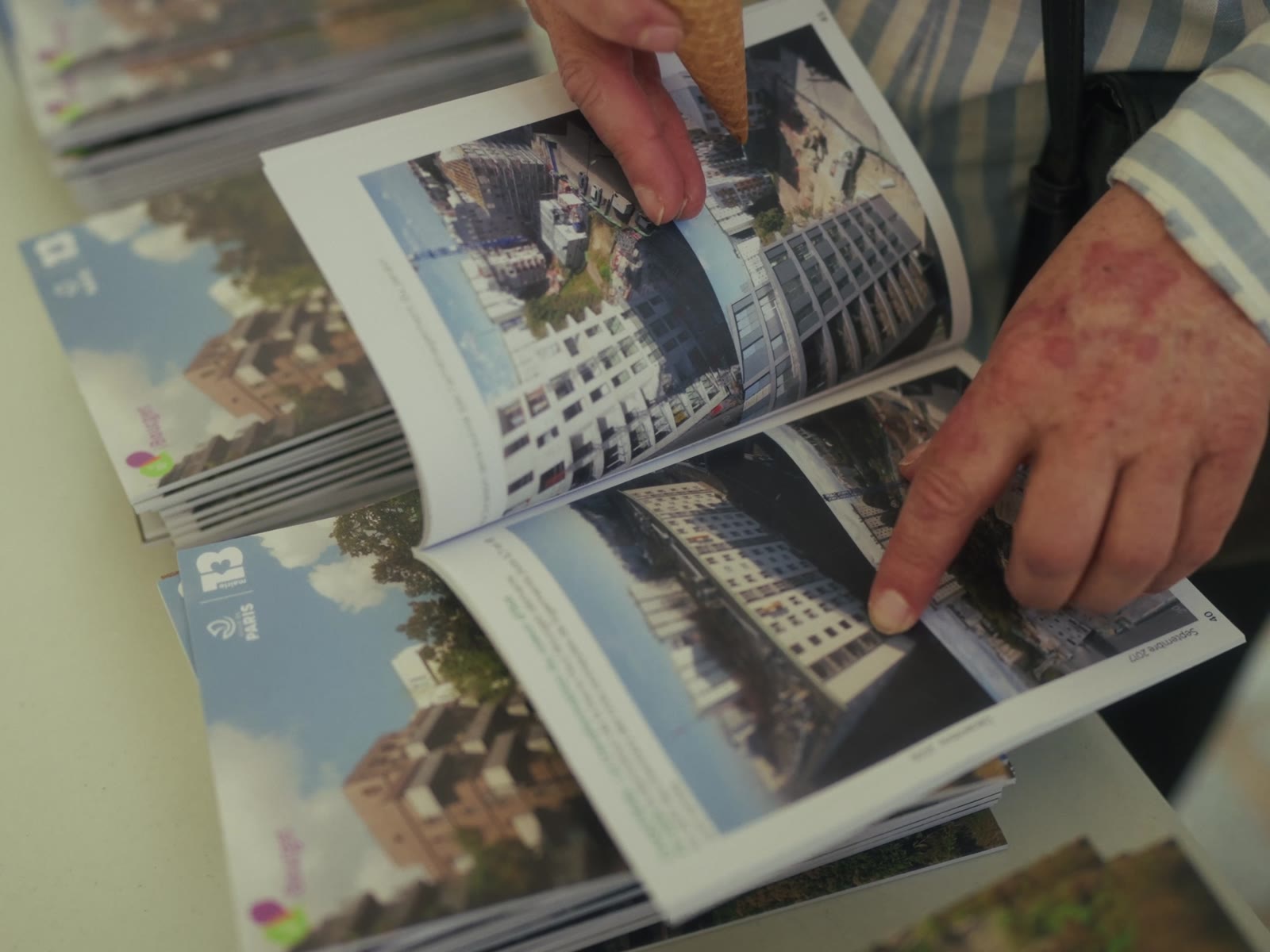 Des mains feuillettent un livre de photographies de la cité