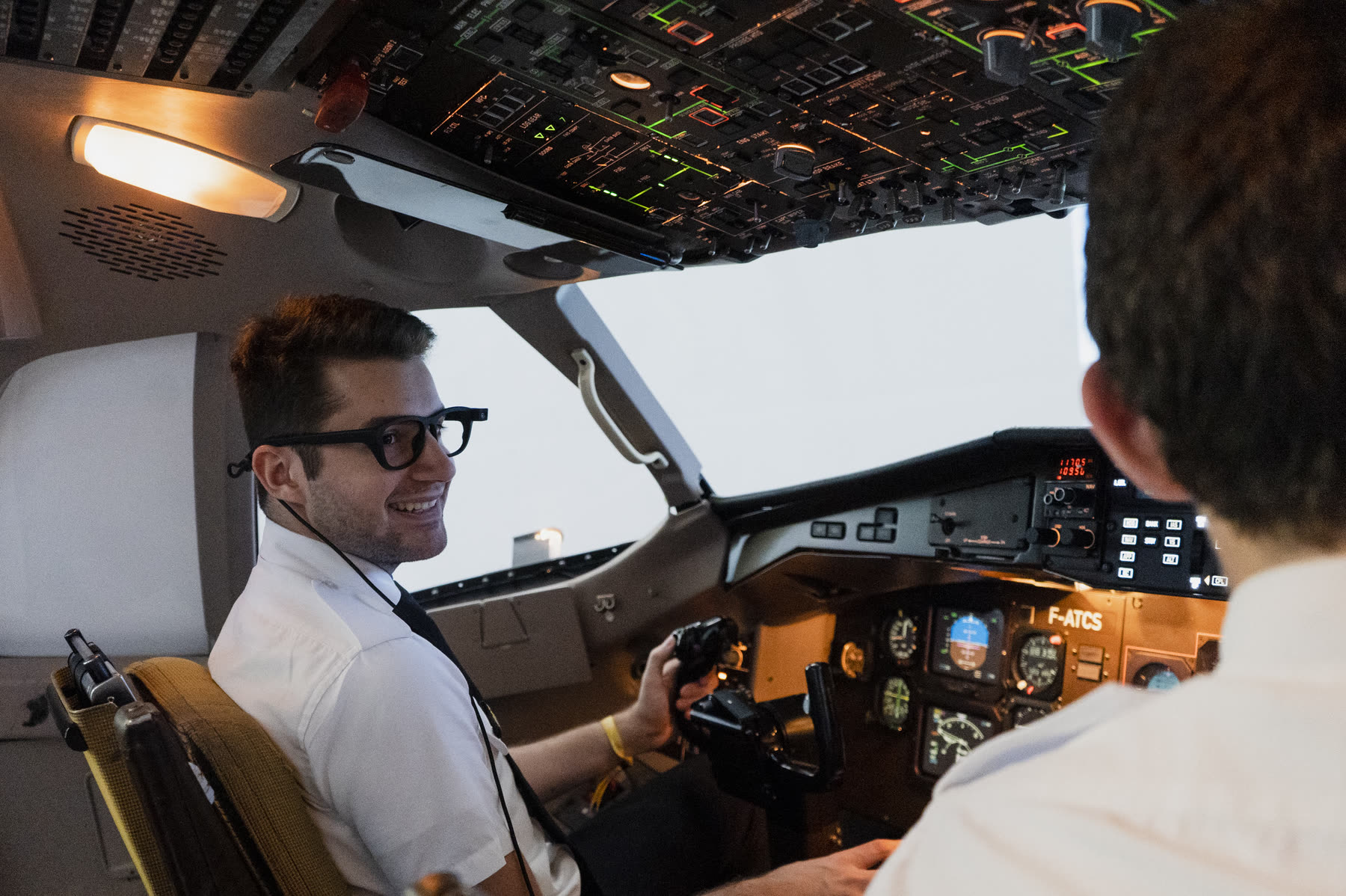 Un élève pilote souriant aux commandes, dans le cockpit