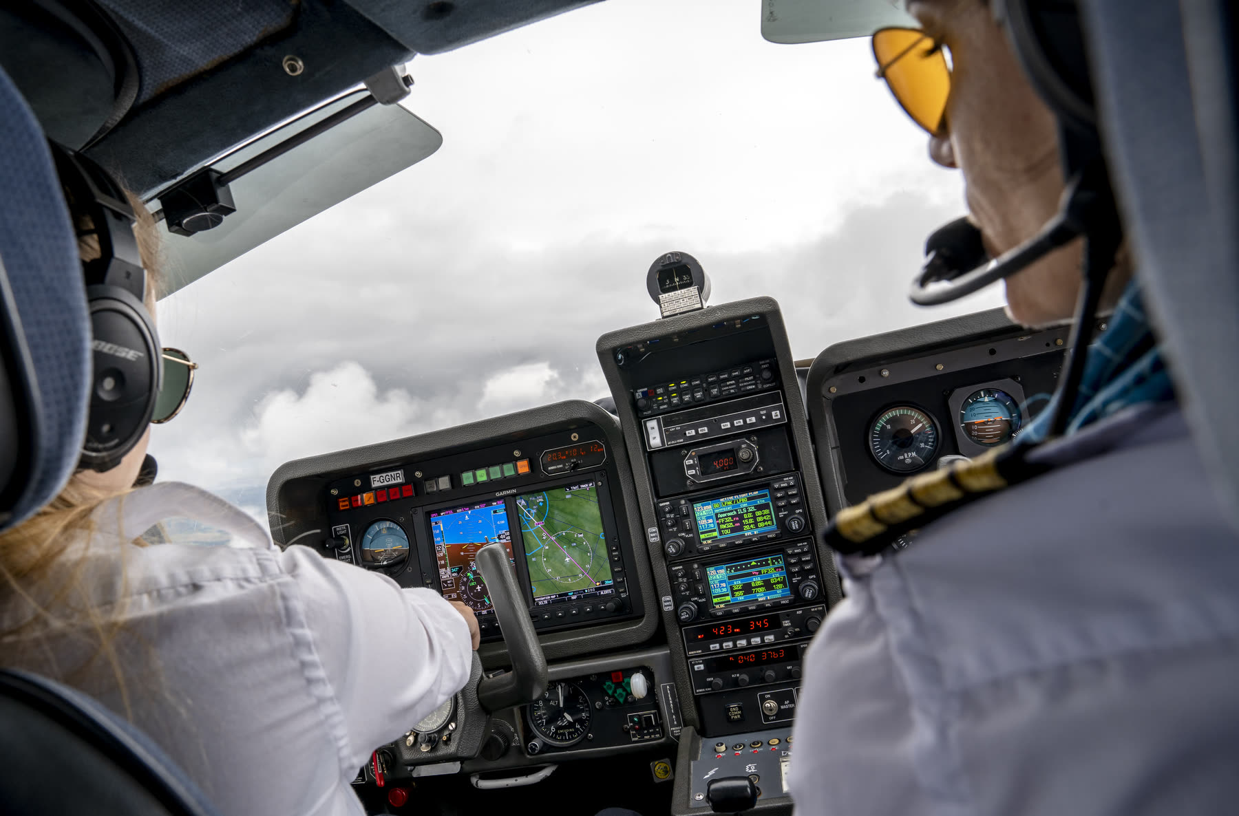 Une élève et son instructeur en vol, devant les écrans du cockpit